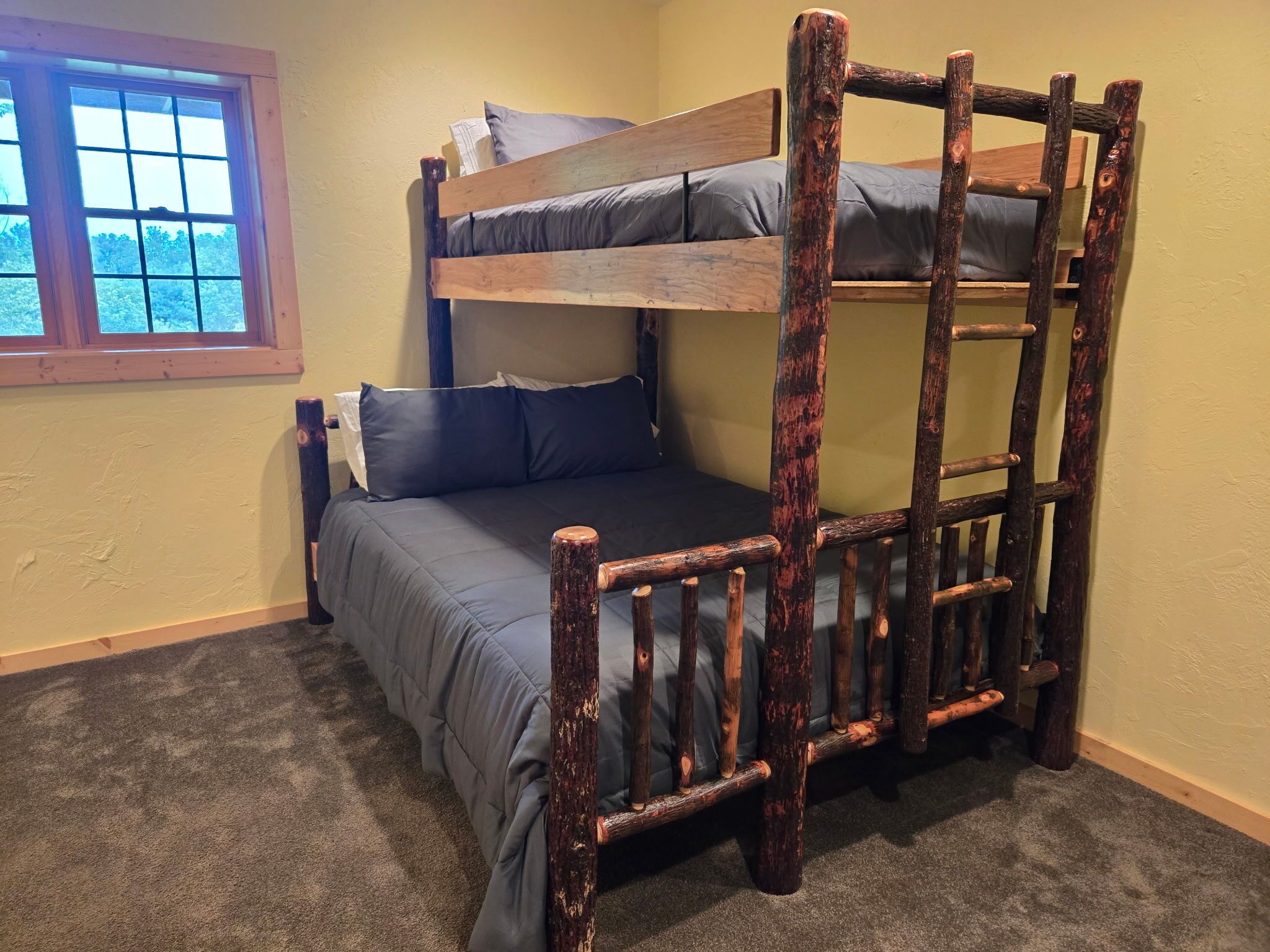 A bunk bed with a ladder, a window, and a carpeted floor.