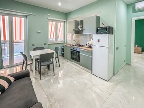 Una cocina moderna con estufa a gas, horno, microondas y refrigerador. Hay un comedor con mesa y sillas.