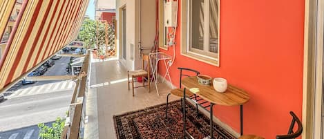 A balcony with a patterned rug, a small table, and chairs.