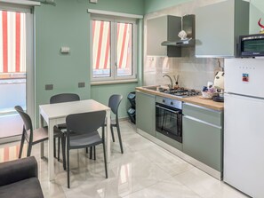 Una cocina compacta con una mesa de comedor, sillas, estufa, horno y refrigerador.