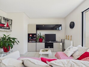 Un salon moderne comprenant un canapé, une table basse, un téléviseur et une bibliothèque.