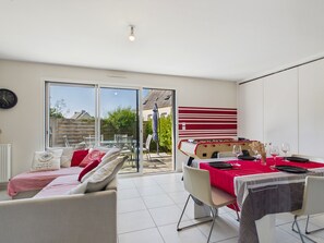 Un salon moderne avec un canapé, une table à manger dressée pour deux personnes et une table de baby-foot.