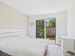 A bedroom with a bed, a desk, and a sliding glass door leading to an outdoor area. - House for 4, Jacuzzi & Garden, Beach 200 m Away (Plouguerneau)