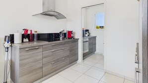 Una cocina moderna con armarios grises, una campana extractora de acero inoxidable y un ventanal que proporciona luz natural.