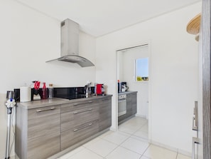 A modern kitchen with grey cabinetry, a stainless steel range hood, and a window providing natural light. - House for 4, Jacuzzi & Garden, Beach 200 m Away (Plouguerneau)
