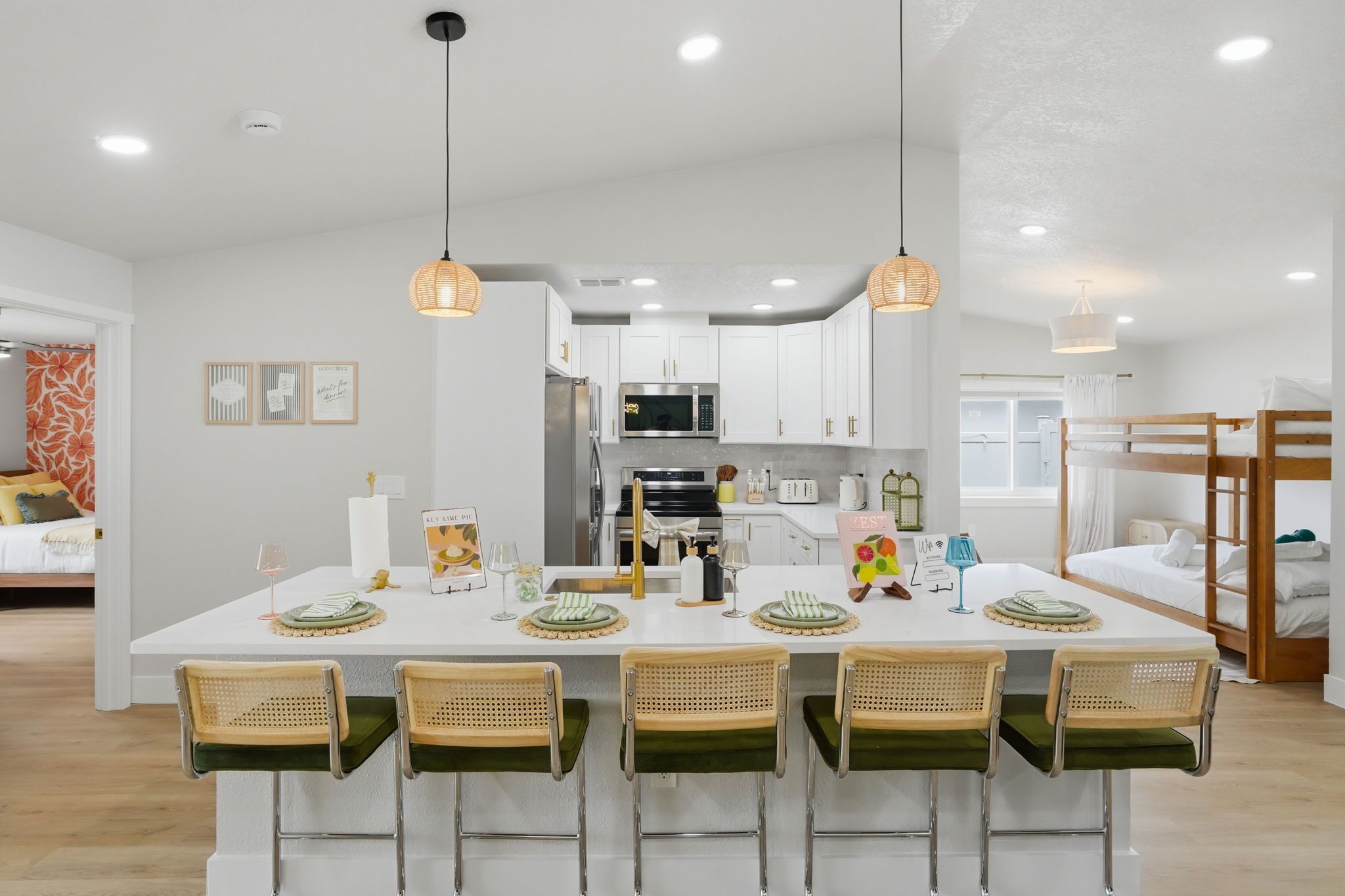 A modern kitchen with white cabinets, a central island with bar stools, and pendant lighting.