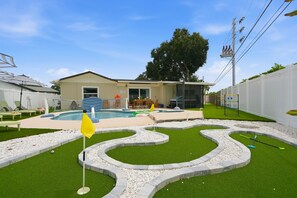 A backyard with a swimming pool, a patio area, and a lawn. - Pickleball, Hot Tub, Pool, Mini Golf, Arcades, Billiards, and More! (St. Petersburg)