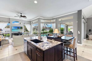A spacious living area with a large island, a dining table, and a seating arrangement. - Waterfront Retreat - Private Pool - Large Dock (Marco Island)
