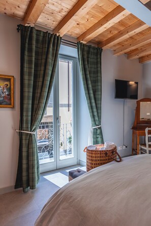 A bedroom with a bed, a television, and a window with curtains.