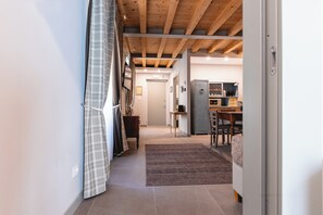 A hallway leading to a kitchen with a dining area, a door, and a coat rack.