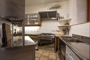 A compact kitchen with a gas stove, oven, stainless steel sink, and white tiled walls. - Huge amazing chalet with 13 bedrooms, private garden and en-suites (Vaujany)