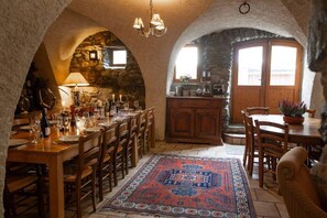 A rustic kitchen with stone walls, wooden furniture, and a central island. - Huge amazing chalet with 13 bedrooms, private garden and en-suites (Vaujany)