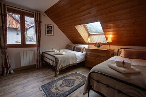 Ein gemütliches Schlafzimmer mit zwei Betten, einem Oberlicht, Holzboden und Blick ins Freie.