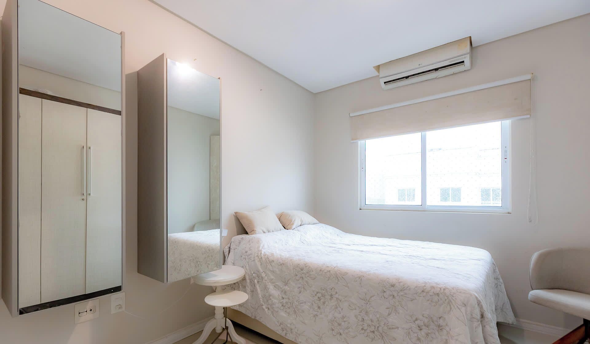 A bedroom with a bed, a chair, a wardrobe, and a window.