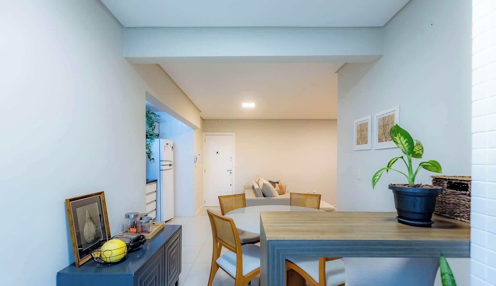 A compact kitchen with white cabinets, a refrigerator, and a dining area with a table and chairs.