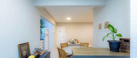 Une cuisine compacte avec des meubles blancs, un réfrigérateur et un coin repas comprenant une table et des chaises.