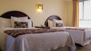 Habitación de hotel con dos camas, cada una con una colcha estampada, teléfono en la mesita de noche y una lámpara fijada a la pared.