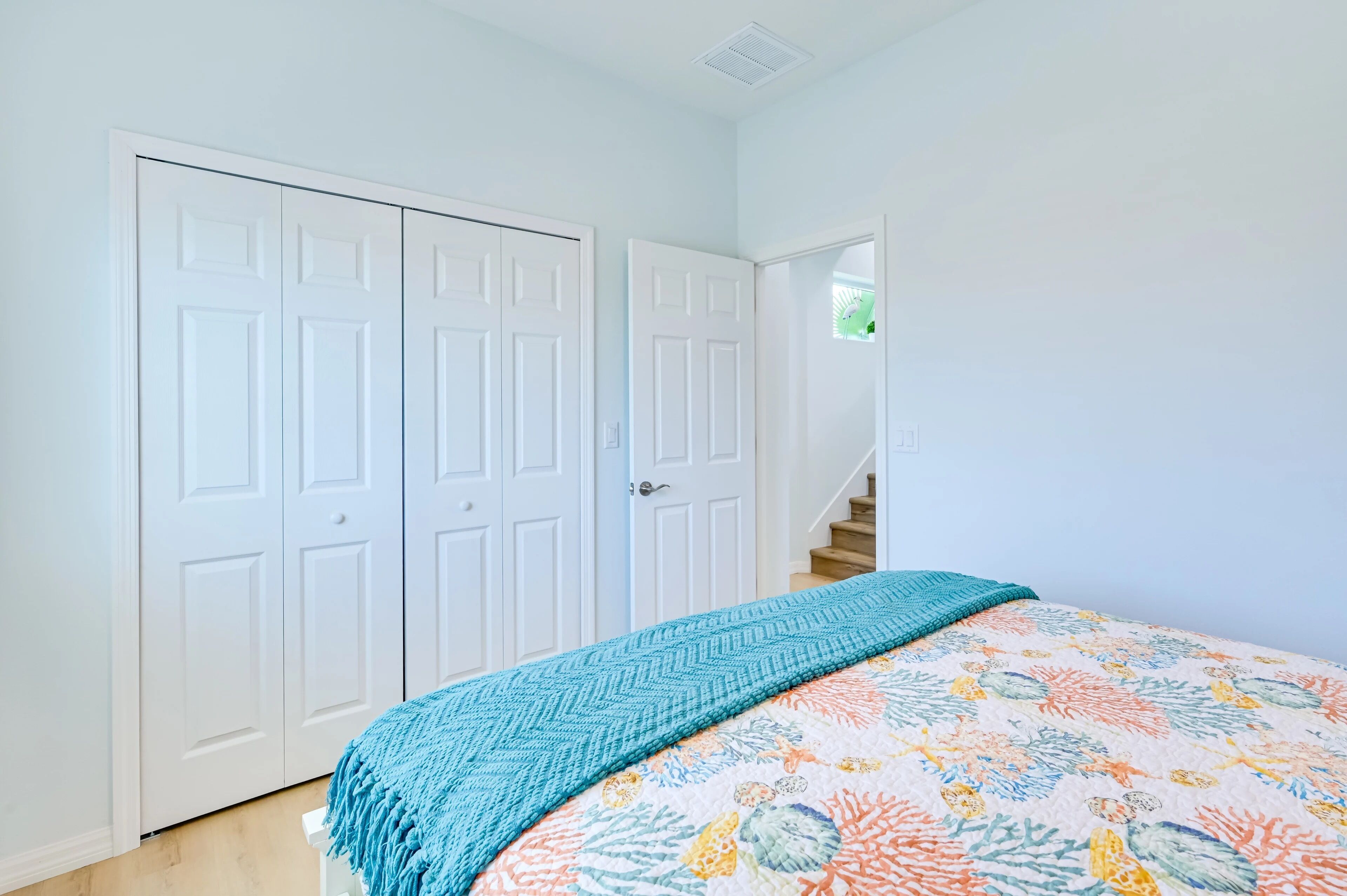 A bedroom with a bed, a door, and a staircase.