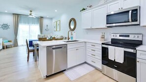 A modern kitchen with white cabinetry, a dishwasher, a microwave, and an oven. - Waterfront Duplex with boat dock (Hudson)