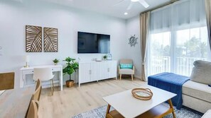 A modern living room with a flat-screen TV, a dining table, and a sofa. - Waterfront Duplex with boat dock (Hudson)