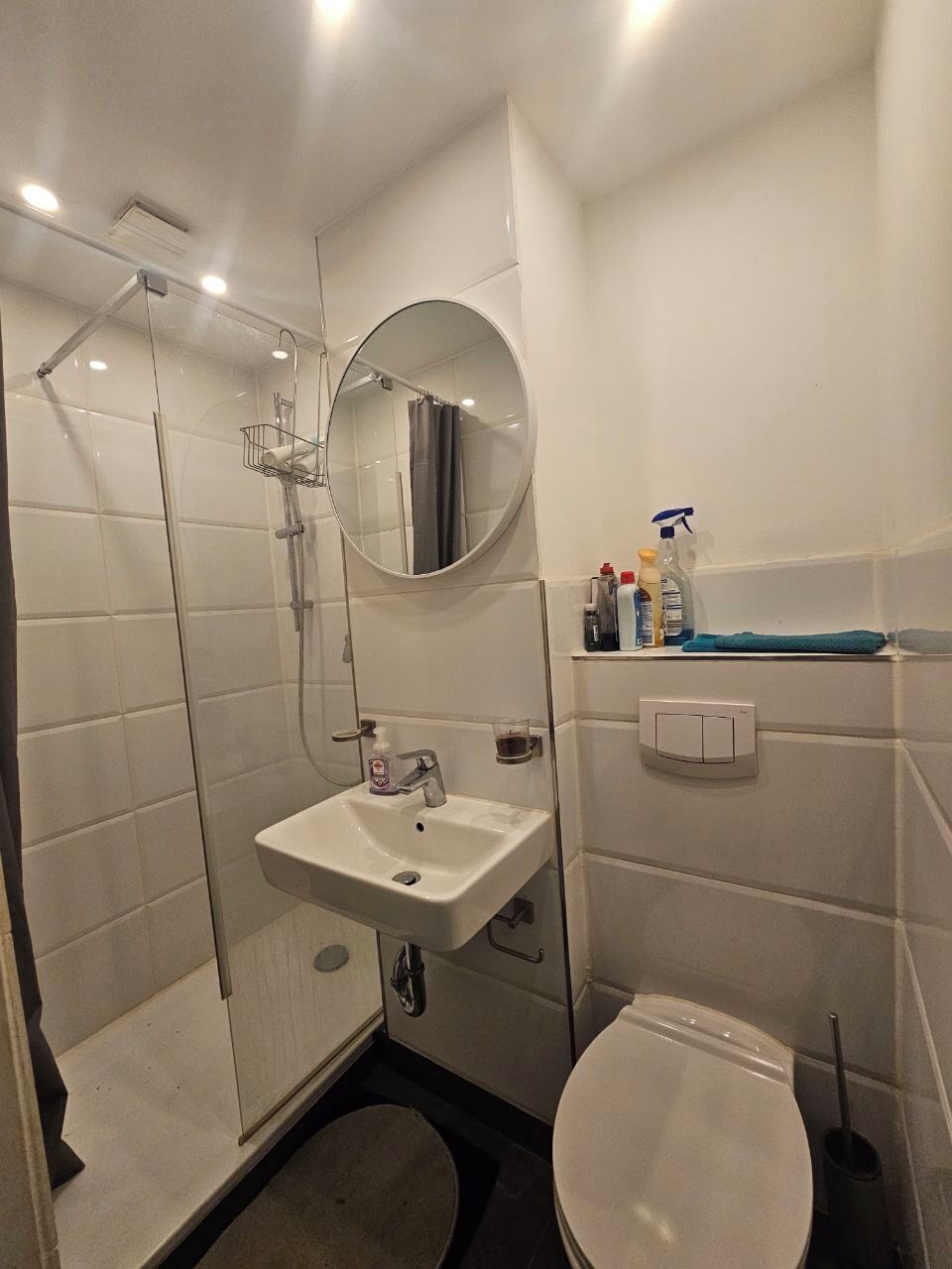 Ein Badezimmer mit Dusche, Waschbecken, Toilette und Spiegel.
