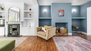 Una sala de estar con chimenea, un sofá y una jaula para perro.