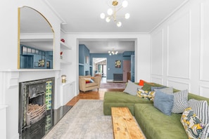 Ein Wohnzimmer mit Kamin, einem grünen Sofa und einem Holztisch.