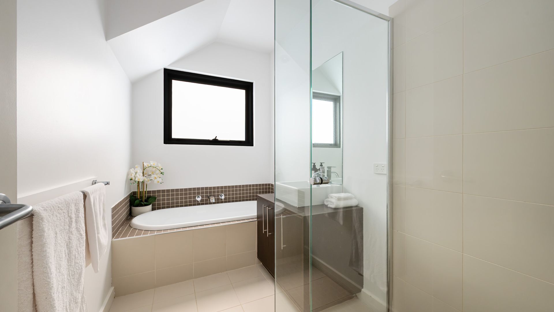 A modern bathroom with a bathtub, a glass shower enclosure, a sink, and a mirror.
