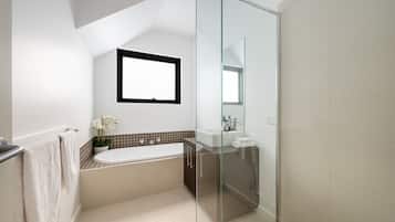 A modern bathroom with a bathtub, a glass shower enclosure, a sink, and a mirror.