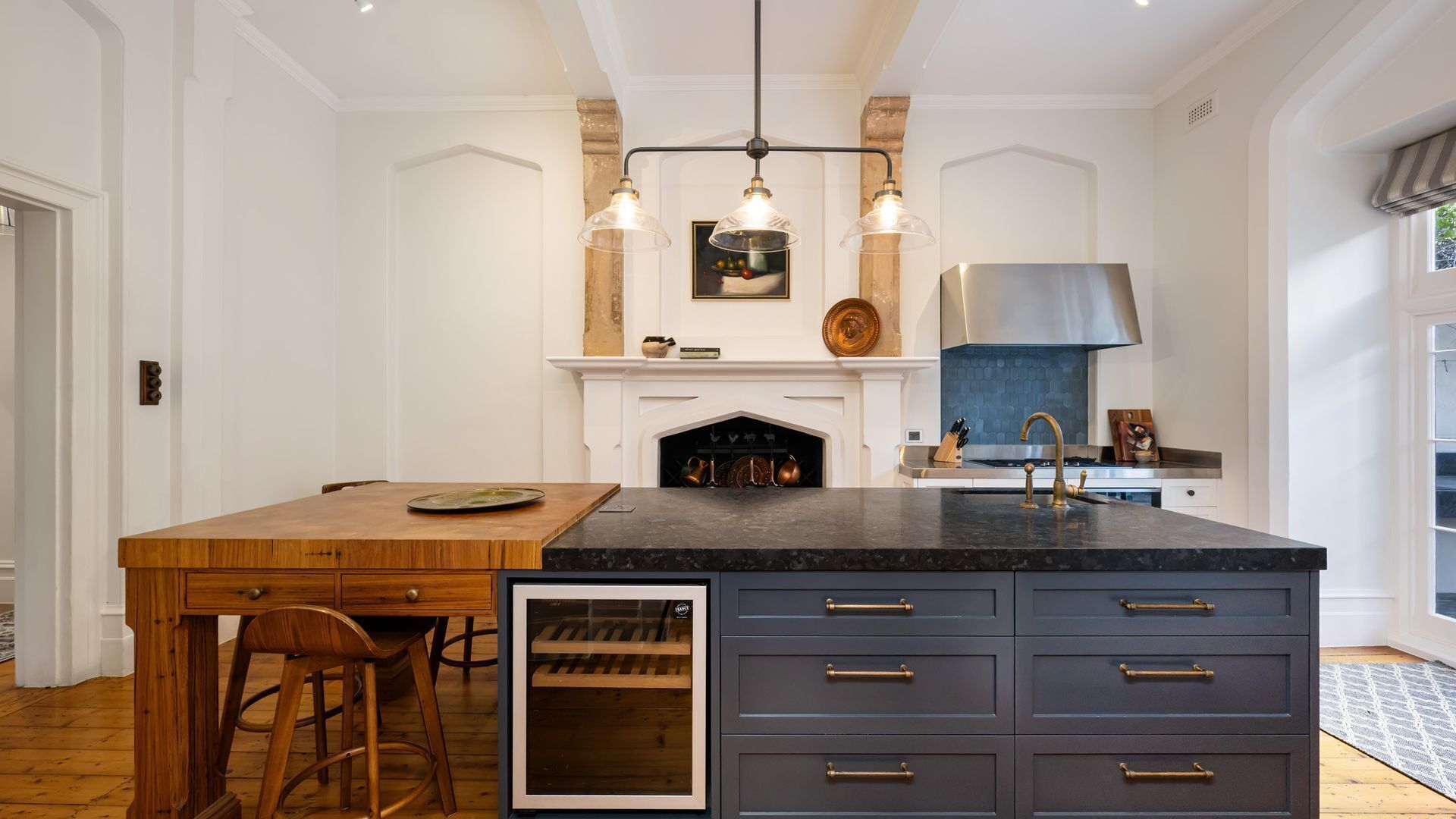 A kitchen with a central island, a built-in wine cooler, and a large window.