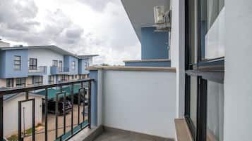 A balcony with a view of neighboring buildings and parked cars.