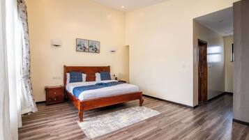 A bedroom with a wooden bed, a nightstand, a wall-mounted lamp, and a painting.