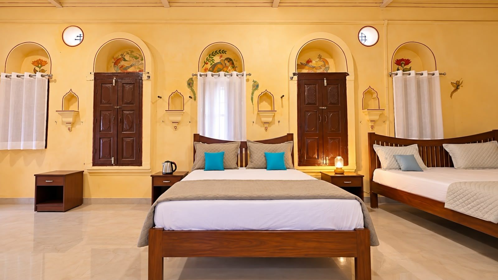Une chambre d’hôtel avec un grand lit, deux tables de chevet, une petite table et une lampe fixée au mur.