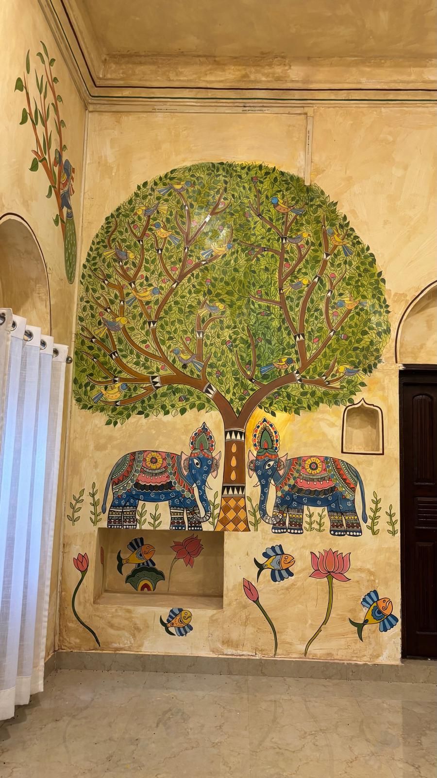 A wall mural with a tree, elephants, and birds.