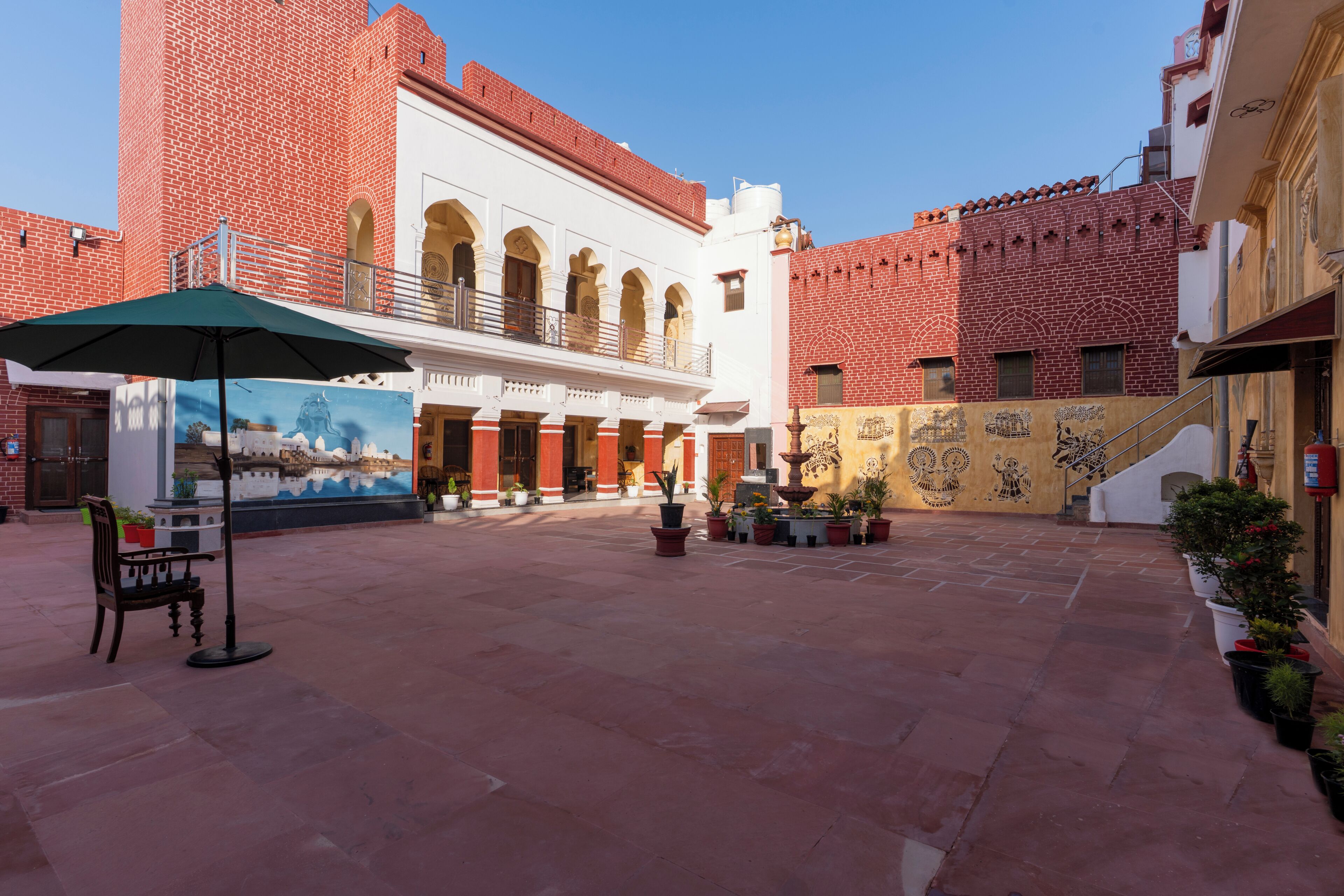 A courtyard with a mural, a fountain, and a bench.
