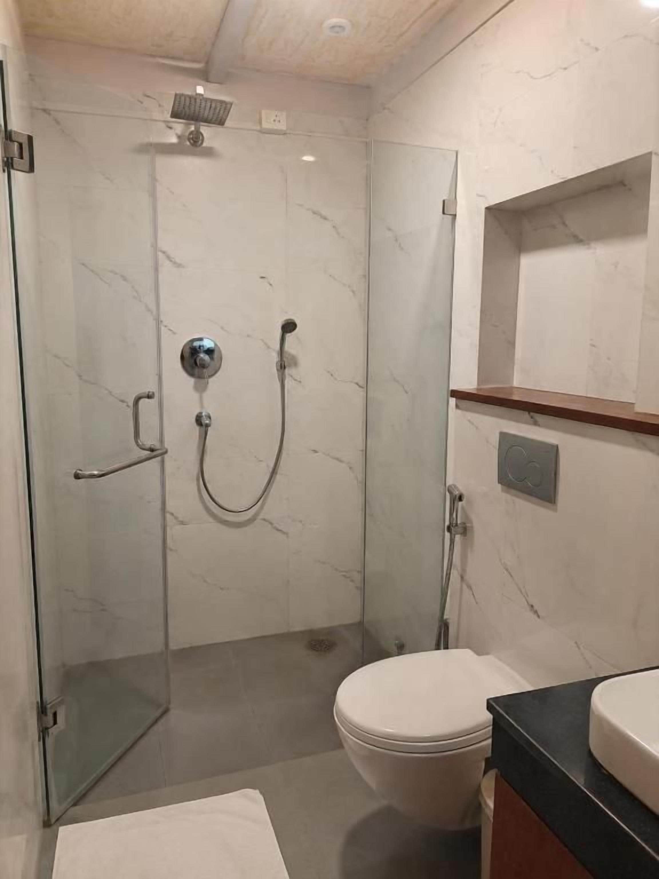 A modern bathroom with a glass-enclosed shower, a toilet, and a sink with a black countertop.