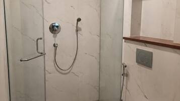 A modern bathroom with a glass-enclosed shower, a toilet, and a sink with a black countertop.