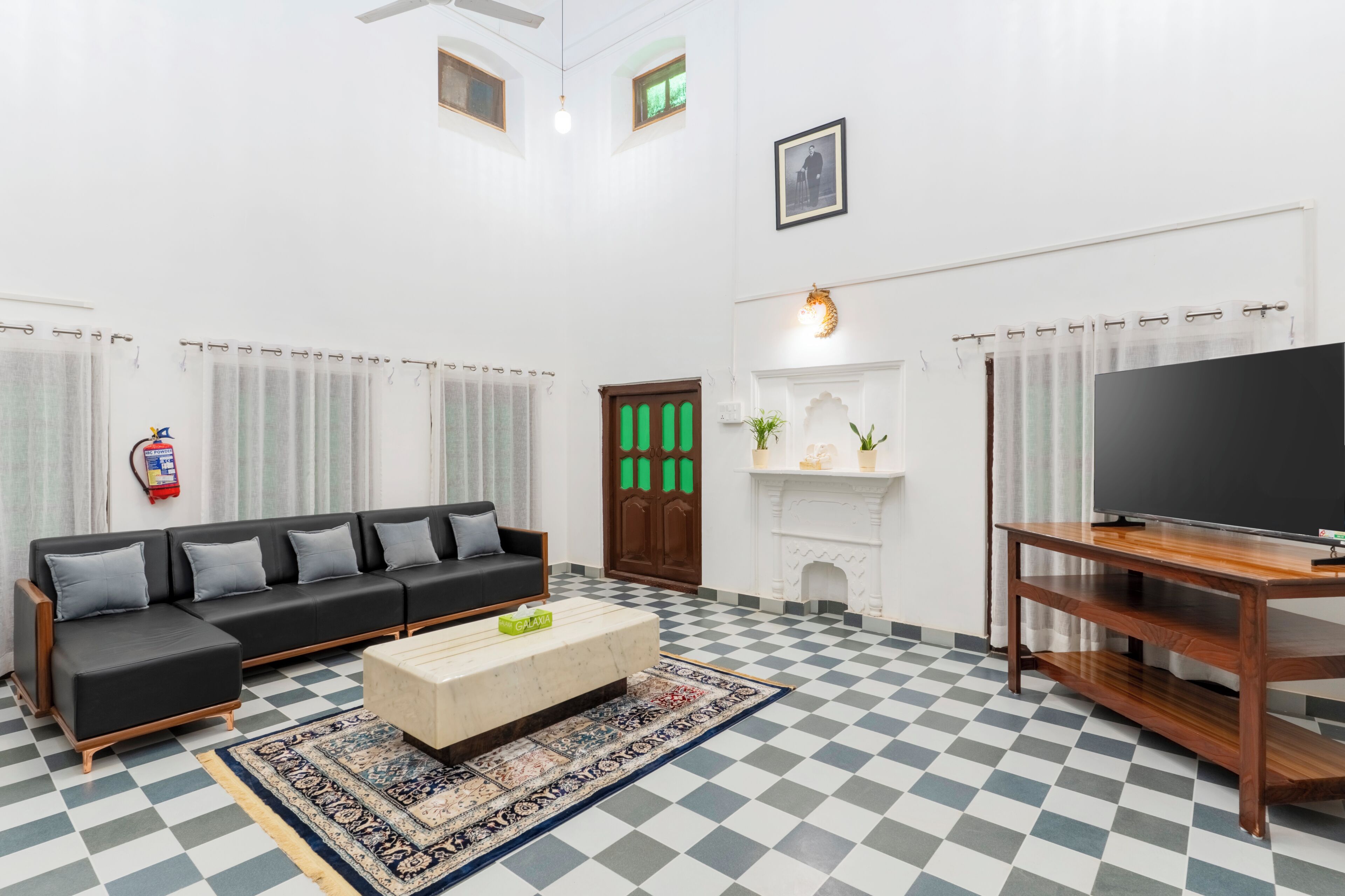 A living room with a sofa, a television, a fireplace, and a checkered floor.