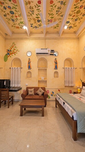 A room with a sofa, a bed, a table, and a ceiling fan.