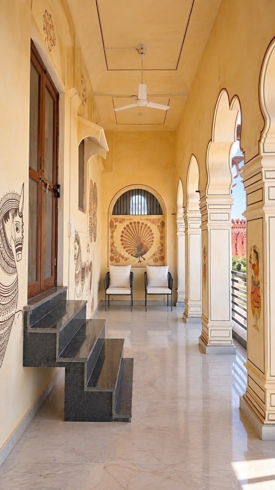A corridor with a ceiling fan, a mural, and a staircase leading to an upper level.