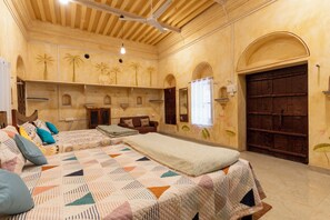 Une pièce avec un grand lit, une armoire en bois, une fenêtre avec des rideaux et une porte.