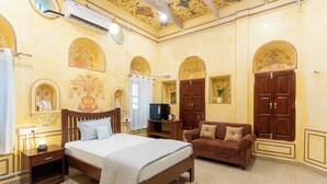 Habitació d'hotel amb llit, sofà, televisió i decoració mural.