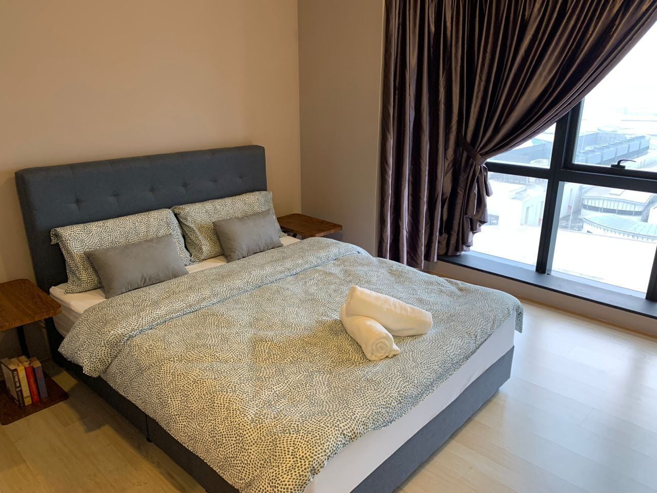 Ein modernes Schlafzimmer mit einem großen Bett, einem Nachttisch und einem Fenster mit Vorhängen.