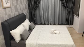 A bed with a white blanket, two pillows, and a rolled towel.
