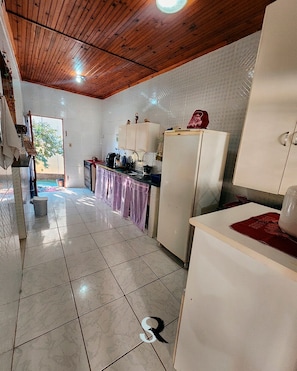 A kitchen with white cabinets, a refrigerator, and a tiled floor.