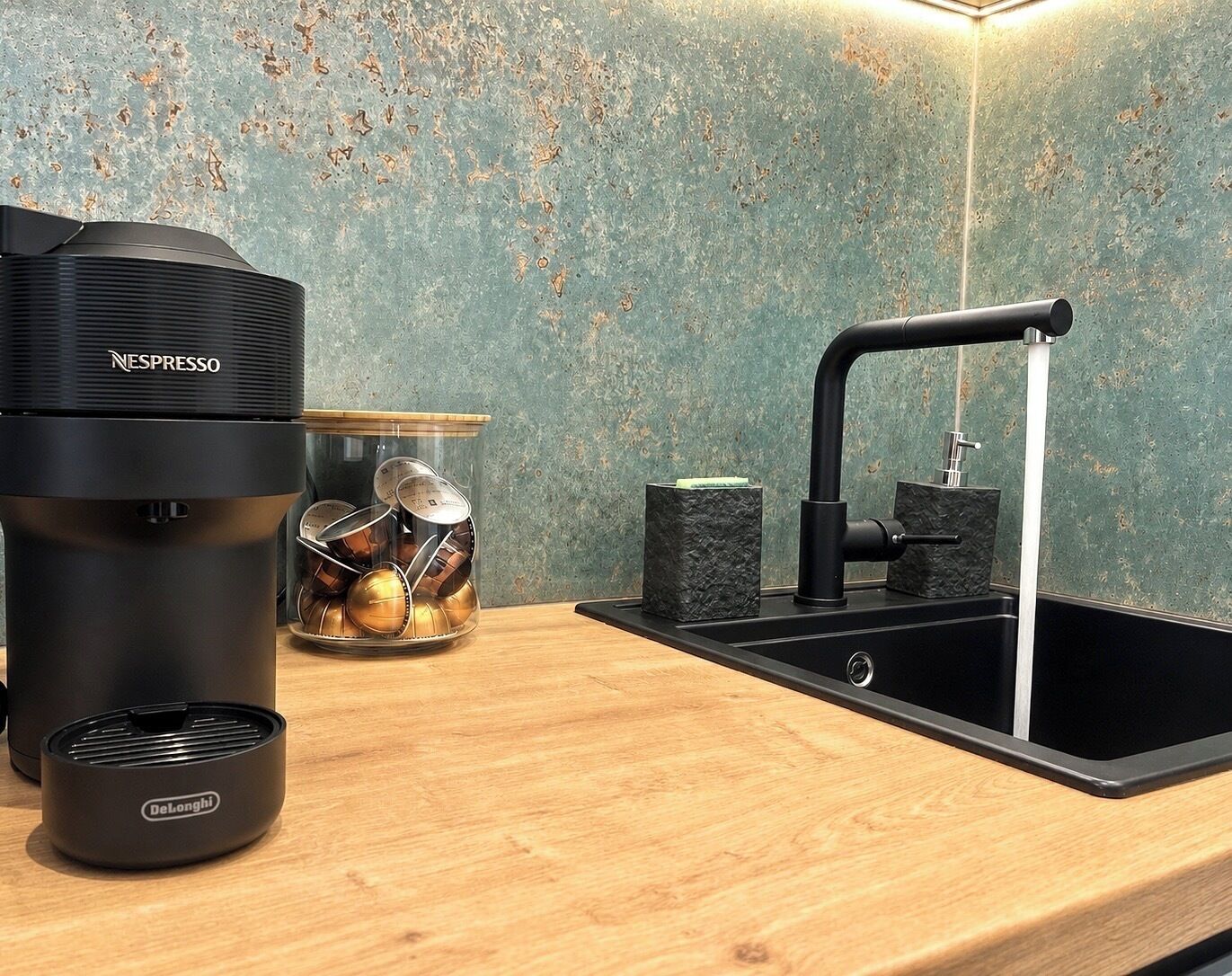 Une cuisine équipée d’une machine à café Nespresso, d’un évier et d’une machine à expresso DeLonghi.