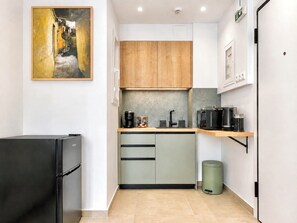 A compact kitchen with a refrigerator, coffee maker, and microwave. - Kypseli Pulse Studio - Metro & Vibes Inside by ΜΡS (Athina)