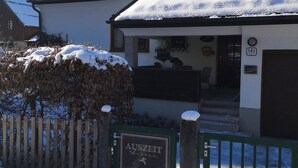 A snow-covered building with a sign reading 'AUSZEIT Hauslee' and a gate.