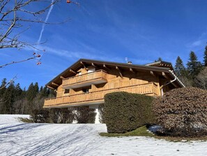 Eine Holzhütte mit Balkon, umgeben von Schnee und Bäumen.