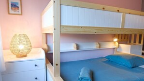 A bunk bed with a wooden frame, a bedside table with a lamp, and a blue bedspread. - Villa Les Issambres avec Piscine,10 Pers (Roquebrune-sur-Argens)